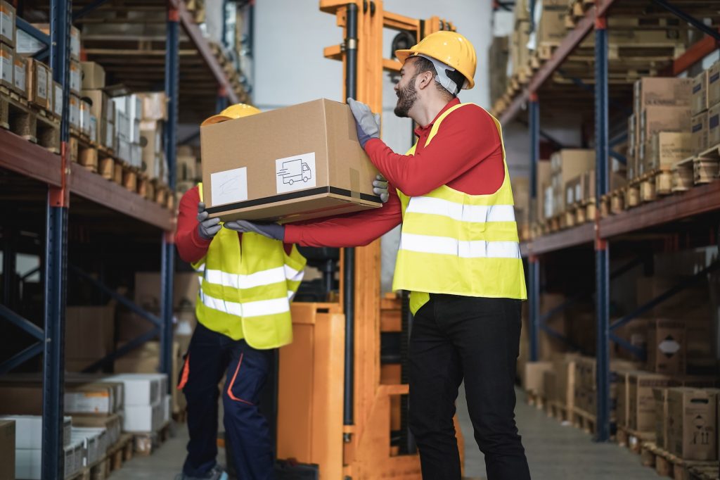 Industrial workers loading delivery box inside warehouse store - Focus on right man